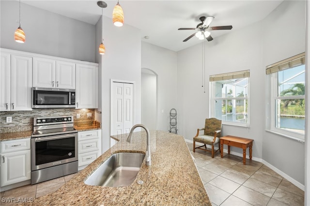 kitchen with white cabinetry, sink, hanging light fixtures, backsplash, and appliances with stainless steel finishes