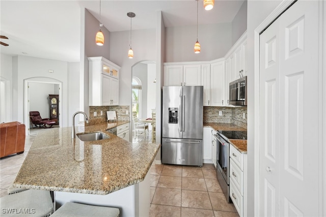 kitchen featuring hanging light fixtures, stainless steel appliances, a high ceiling, kitchen peninsula, and a breakfast bar