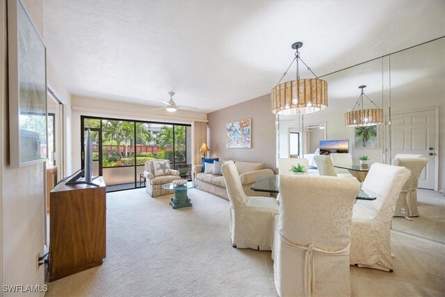 carpeted dining area with ceiling fan with notable chandelier