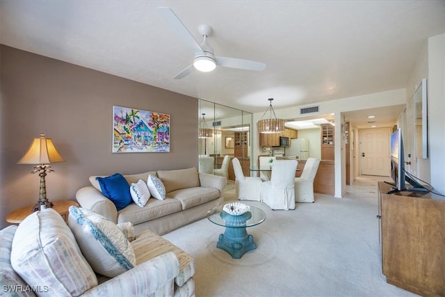 living room with ceiling fan with notable chandelier and light colored carpet