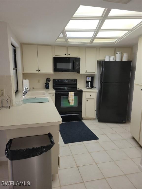 kitchen featuring sink, cream cabinets, and black appliances