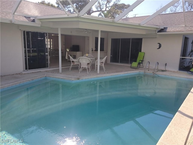 view of swimming pool featuring ceiling fan, glass enclosure, and a patio