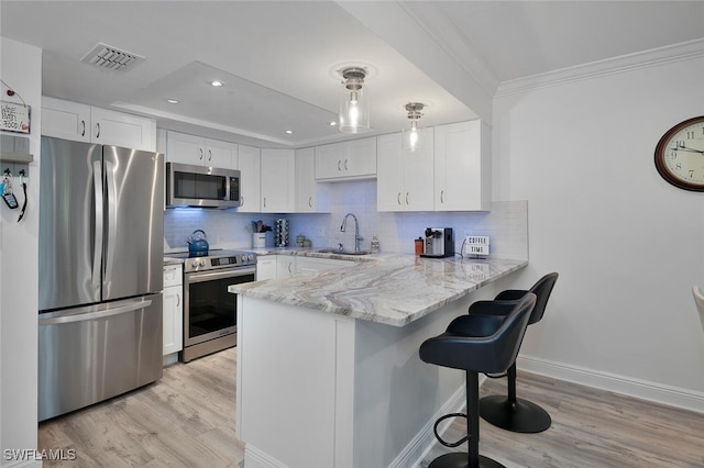 kitchen featuring white cabinets, sink, kitchen peninsula, appliances with stainless steel finishes, and light hardwood / wood-style floors