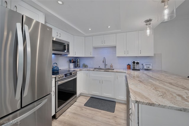 kitchen featuring decorative light fixtures, sink, stainless steel appliances, and white cabinets