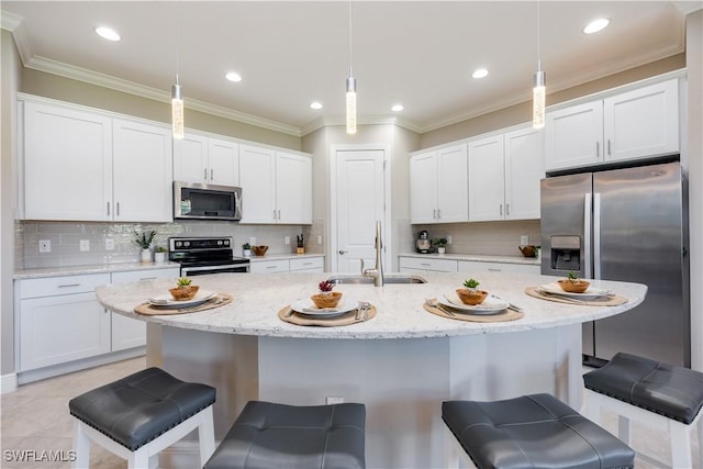 kitchen featuring sink, appliances with stainless steel finishes, a center island with sink, a kitchen bar, and decorative light fixtures