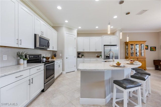 kitchen featuring sink, appliances with stainless steel finishes, light stone counters, white cabinets, and decorative light fixtures