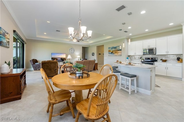 dining area with crown molding, sink, a tray ceiling, and a notable chandelier