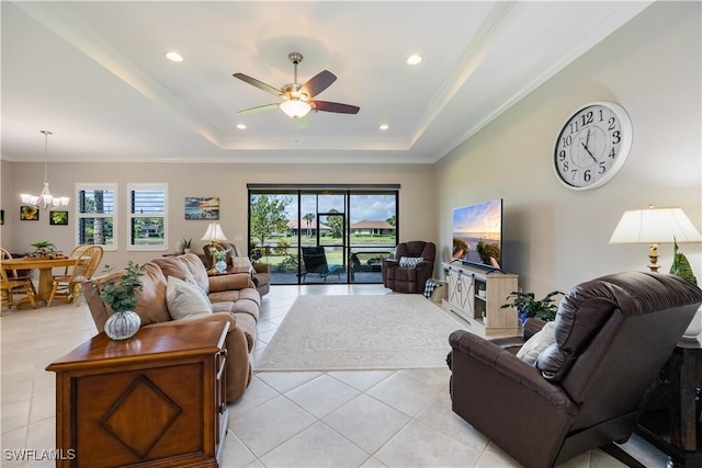 living room with crown molding, a raised ceiling, ceiling fan with notable chandelier, and light tile patterned floors