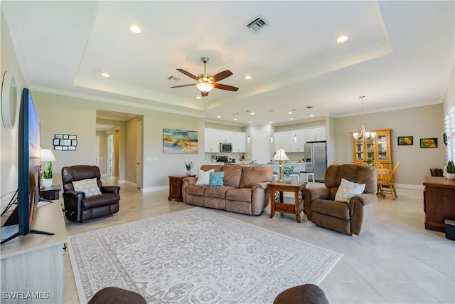 living room with ornamental molding, a tray ceiling, ceiling fan with notable chandelier, and light tile patterned floors