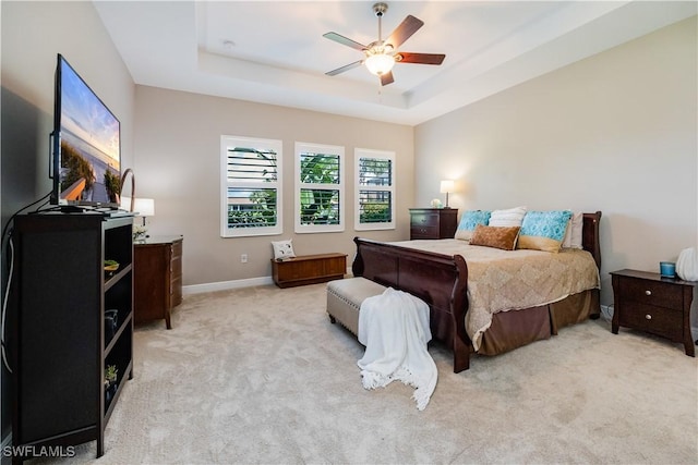 bedroom featuring ceiling fan, a raised ceiling, and light carpet