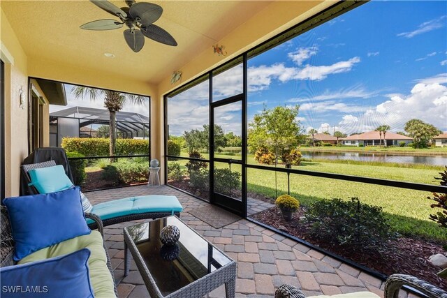 sunroom / solarium featuring a water view and ceiling fan