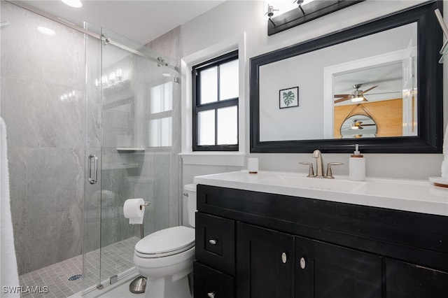 bathroom with vanity, a shower with shower door, toilet, and ceiling fan