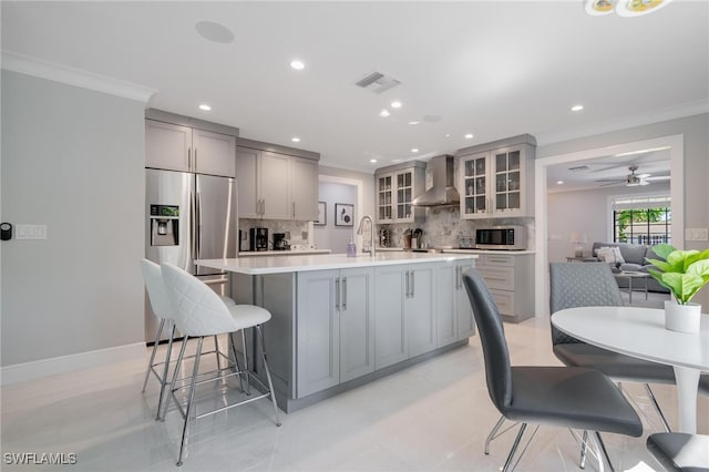 kitchen with wall chimney exhaust hood, appliances with stainless steel finishes, gray cabinetry, and backsplash