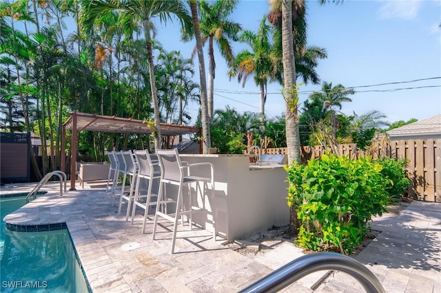 view of patio with exterior bar and a fenced in pool