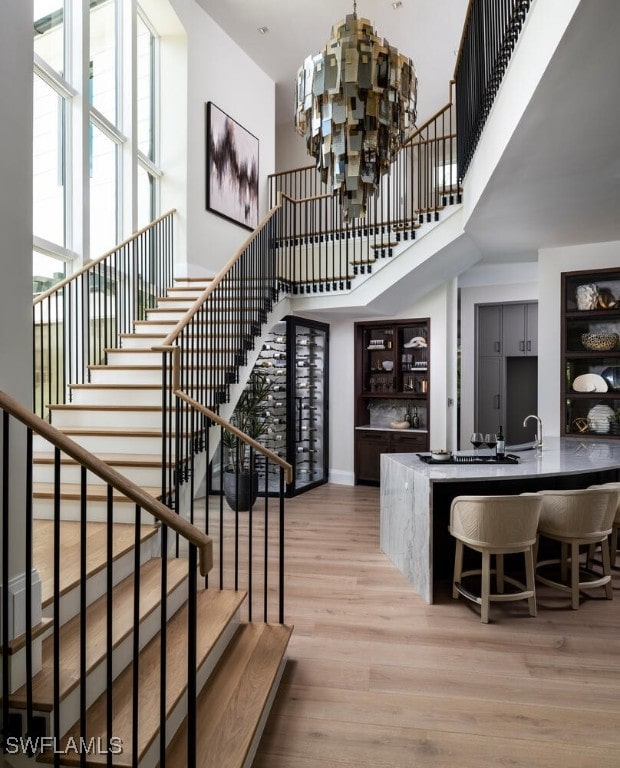 staircase featuring sink, a high ceiling, hardwood / wood-style floors, and a notable chandelier