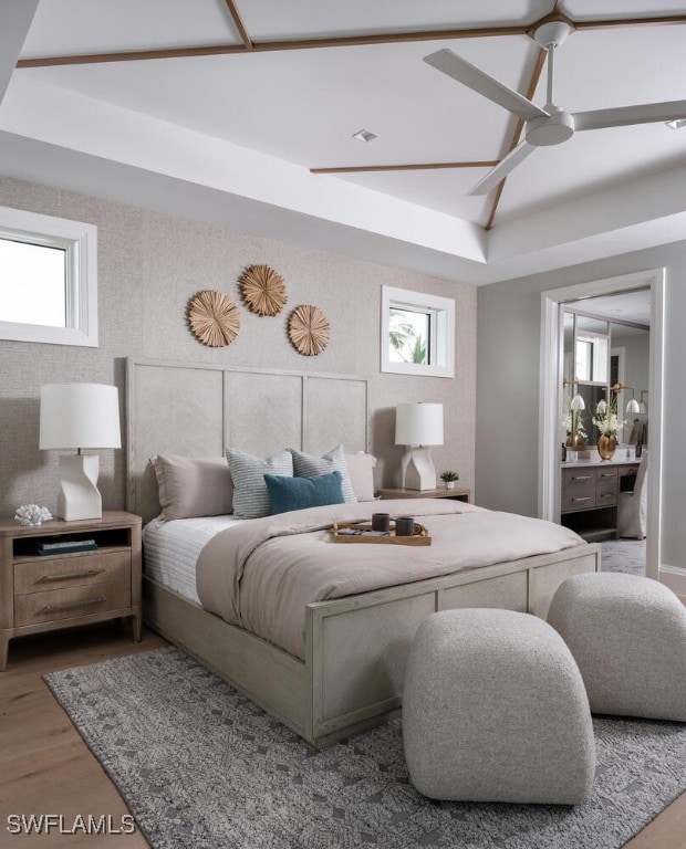 bedroom with wood-type flooring, a raised ceiling, and ceiling fan