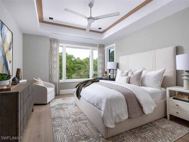 bedroom featuring ceiling fan, a tray ceiling, and light hardwood / wood-style floors