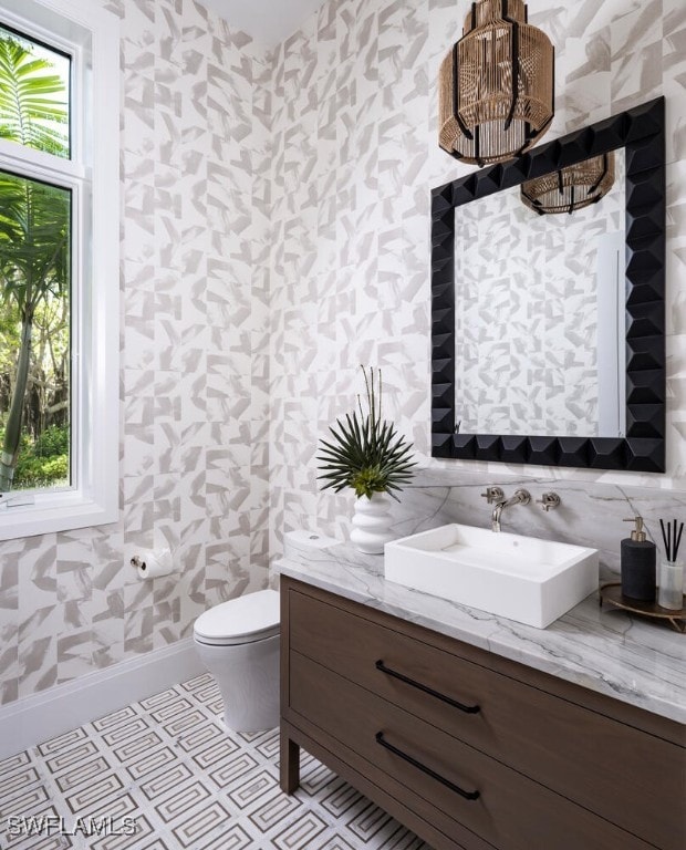 bathroom with toilet, vanity, and plenty of natural light