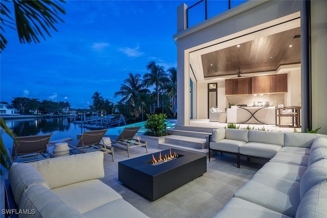 patio terrace at dusk with an outdoor living space with a fire pit and area for grilling