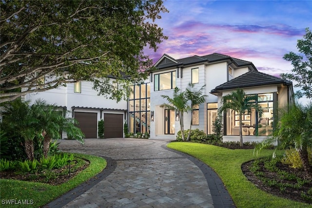 view of front of home with a tile roof, stucco siding, decorative driveway, and an attached garage