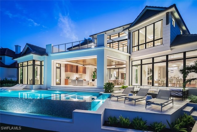 3131 Gin Ln, Naples, FL 34102 - rear view of house featuring a balcony, a patio area, a ceiling fan, an outdoor living space, and an infinity pool