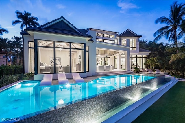 3131 Gin Ln, Naples, FL 34102 - back of property featuring a balcony, an infinity pool, a patio, and stucco siding