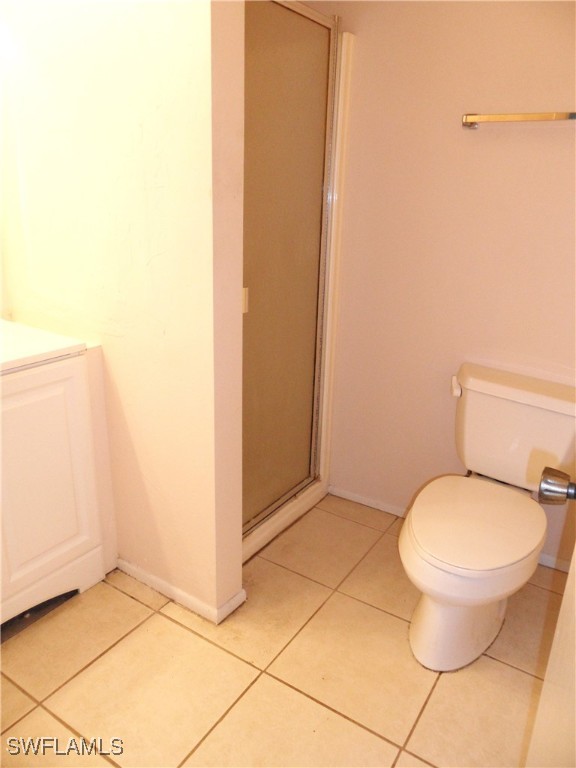 bathroom with tile patterned floors, walk in shower, vanity, and toilet