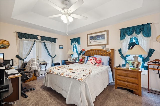 bedroom with ceiling fan, carpet floors, and a tray ceiling