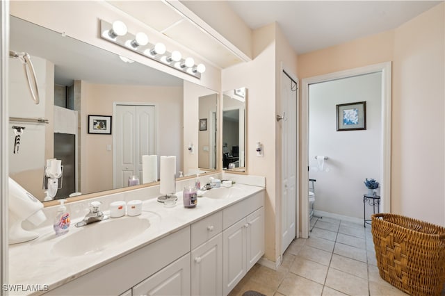 bathroom featuring toilet, vanity, and tile patterned flooring