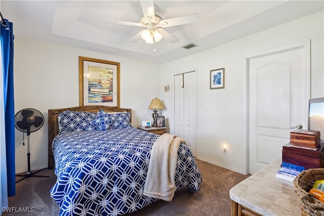 carpeted bedroom featuring ceiling fan, a closet, and a raised ceiling