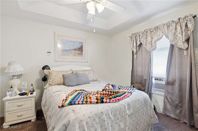 bedroom featuring ceiling fan, dark carpet, a raised ceiling, and cooling unit