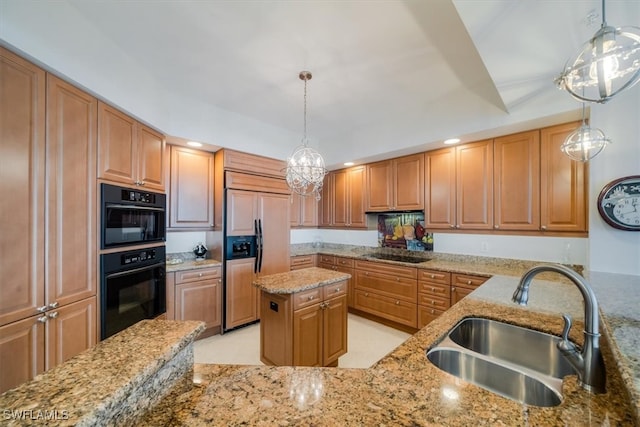 kitchen featuring light stone counters, sink, black appliances, and decorative light fixtures