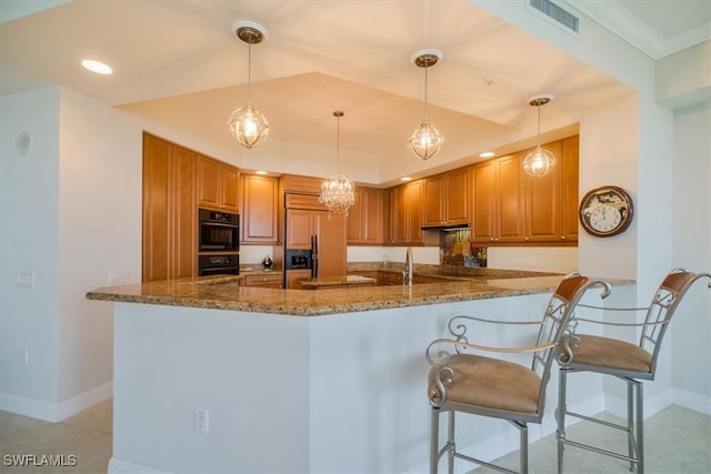 kitchen with pendant lighting, dark stone countertops, paneled fridge, black oven, and kitchen peninsula