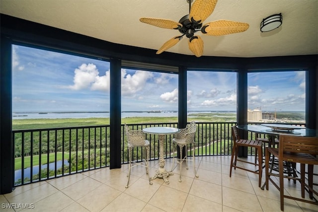 sunroom / solarium with a view of the beach, a water view, and ceiling fan