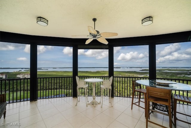 sunroom featuring a water view and ceiling fan