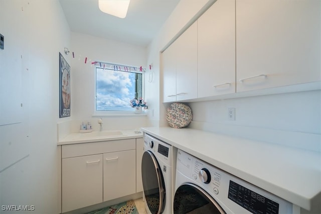 laundry area featuring separate washer and dryer, sink, and cabinets