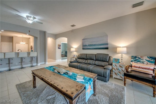 living room featuring light tile patterned floors and ceiling fan with notable chandelier