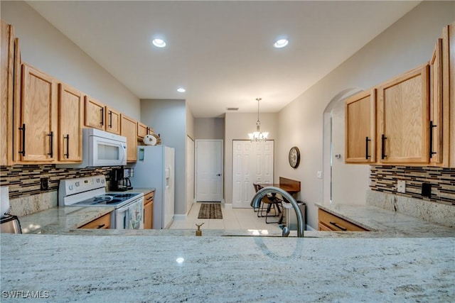 kitchen with sink, white appliances, light stone countertops, and a chandelier