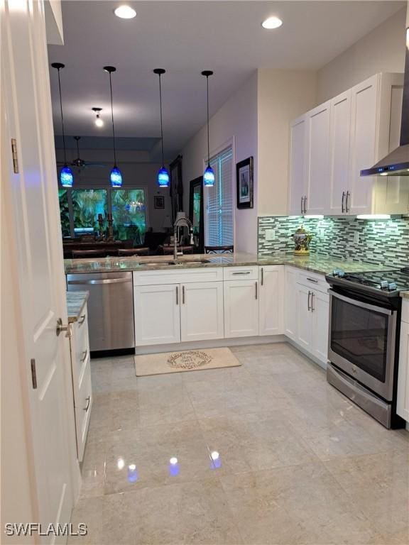 kitchen featuring appliances with stainless steel finishes, white cabinetry, wall chimney exhaust hood, and sink