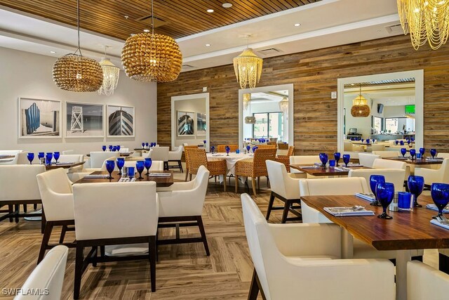 dining space featuring a notable chandelier, wooden walls, parquet floors, and wood ceiling