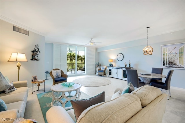 tiled living room with ceiling fan with notable chandelier and ornamental molding