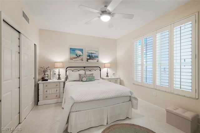 tiled bedroom with ceiling fan and a closet