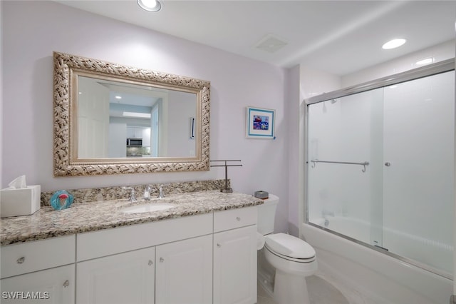 full bathroom featuring vanity, toilet, and combined bath / shower with glass door