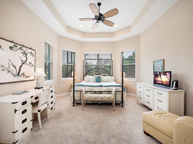 bedroom with a raised ceiling, ceiling fan, and light colored carpet