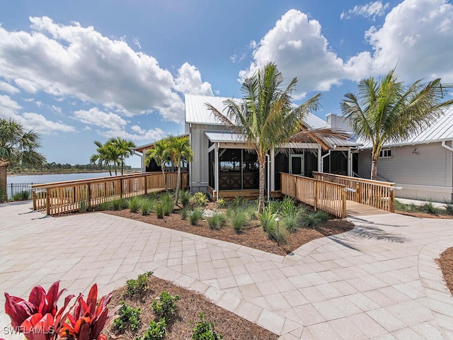 back of house with a sunroom, a patio, and a water view