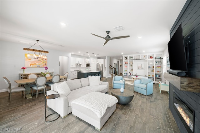 living room featuring hardwood / wood-style flooring and ceiling fan with notable chandelier