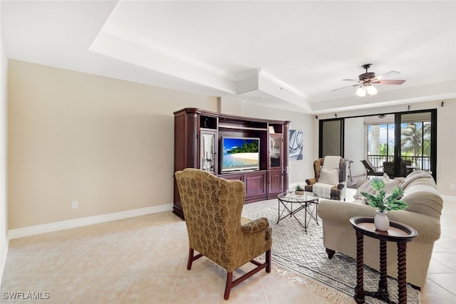 tiled living room with a tray ceiling and ceiling fan