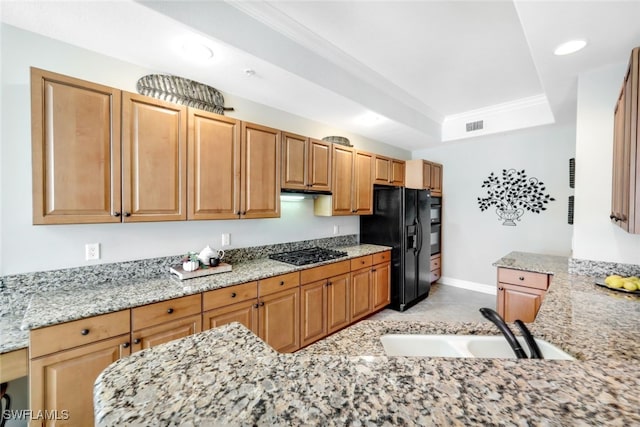 kitchen featuring light tile patterned flooring, sink, black fridge, gas cooktop, and light stone countertops