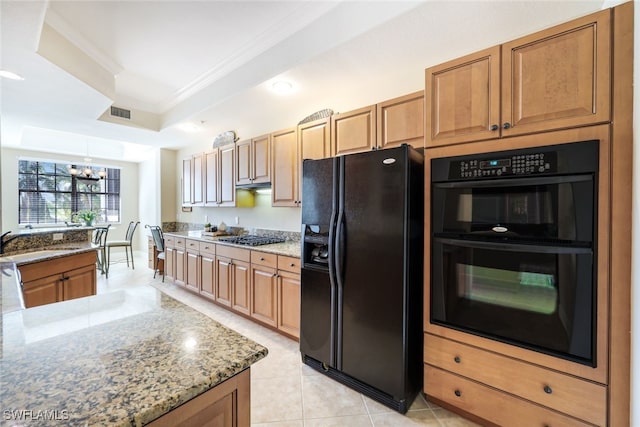 kitchen with crown molding, light stone counters, a notable chandelier, black appliances, and a raised ceiling