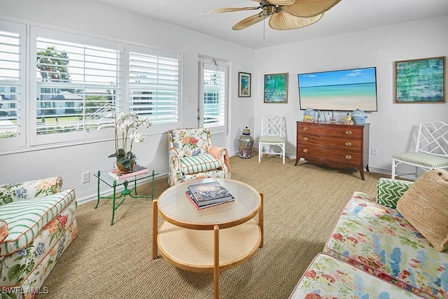 living area with baseboards and ceiling fan